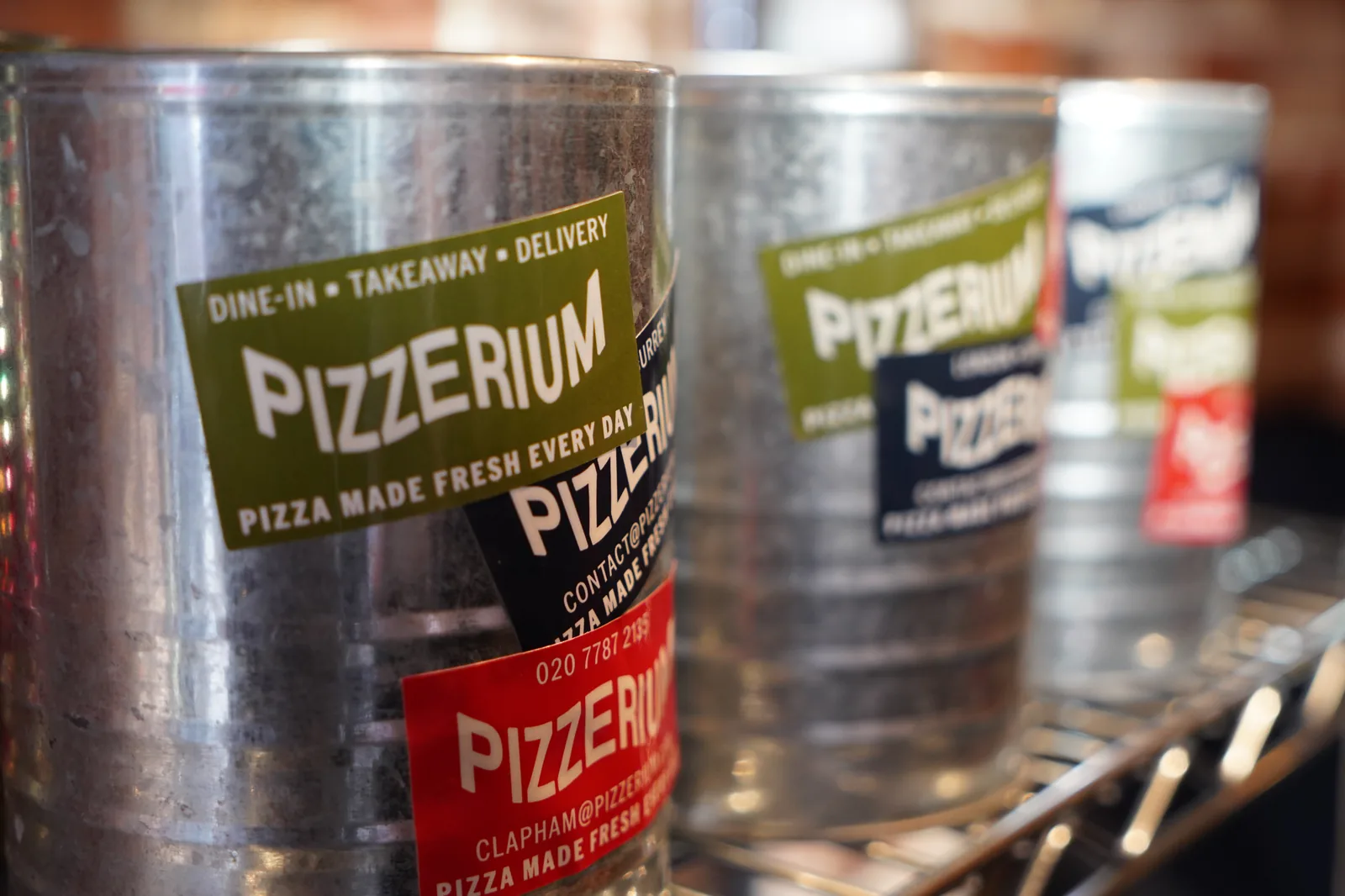 Stacked Pizzerium paper cups with multi-colour brand stickers