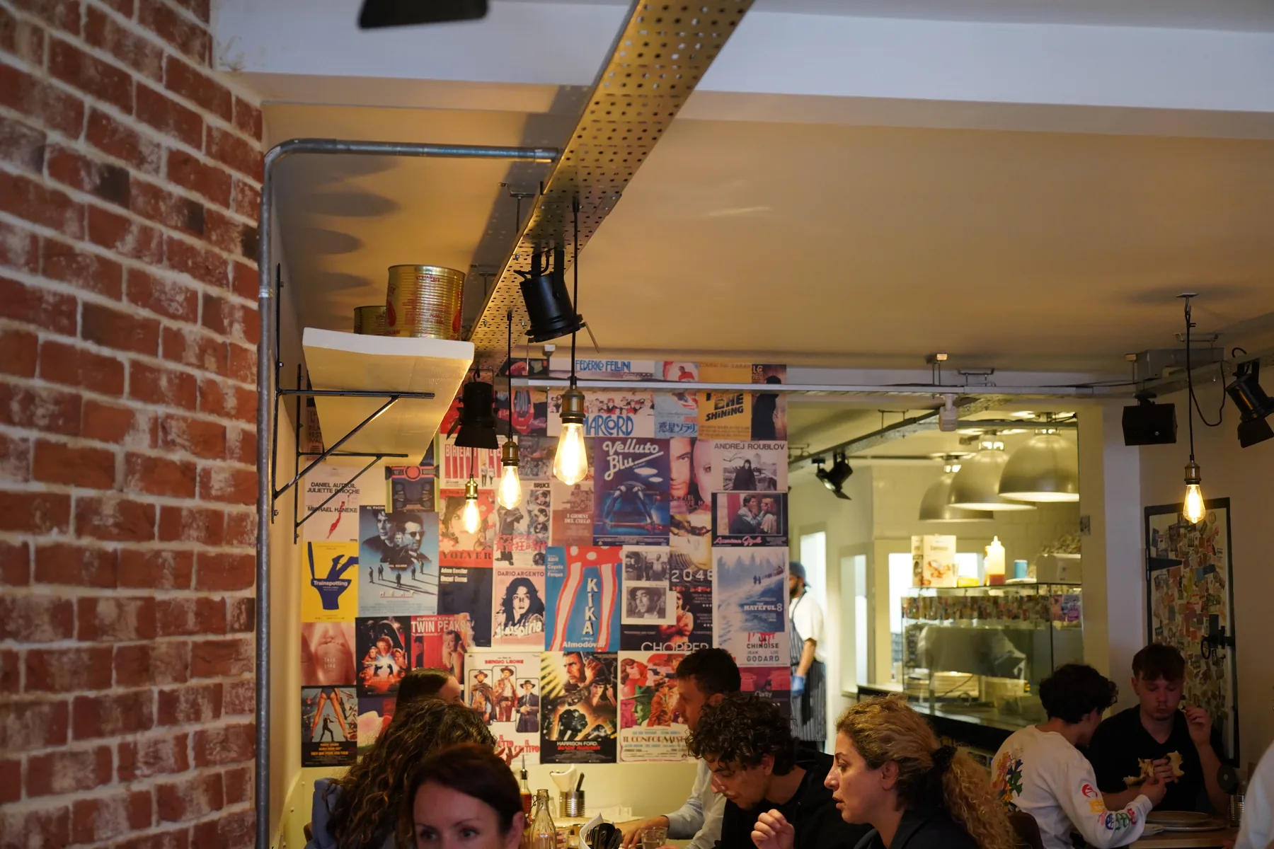 Exposed-brick wall with a gallery of pinned posters and edison bulbs overhead