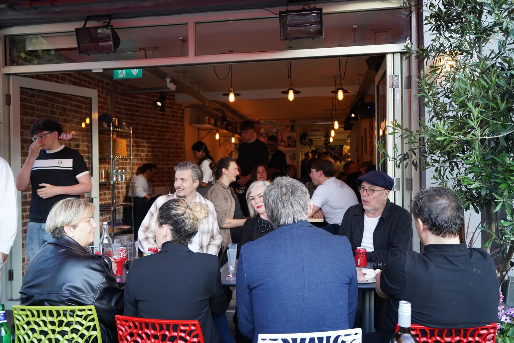 Spillover crowd outside Pizzerium Battersea under the red awning on opening day
